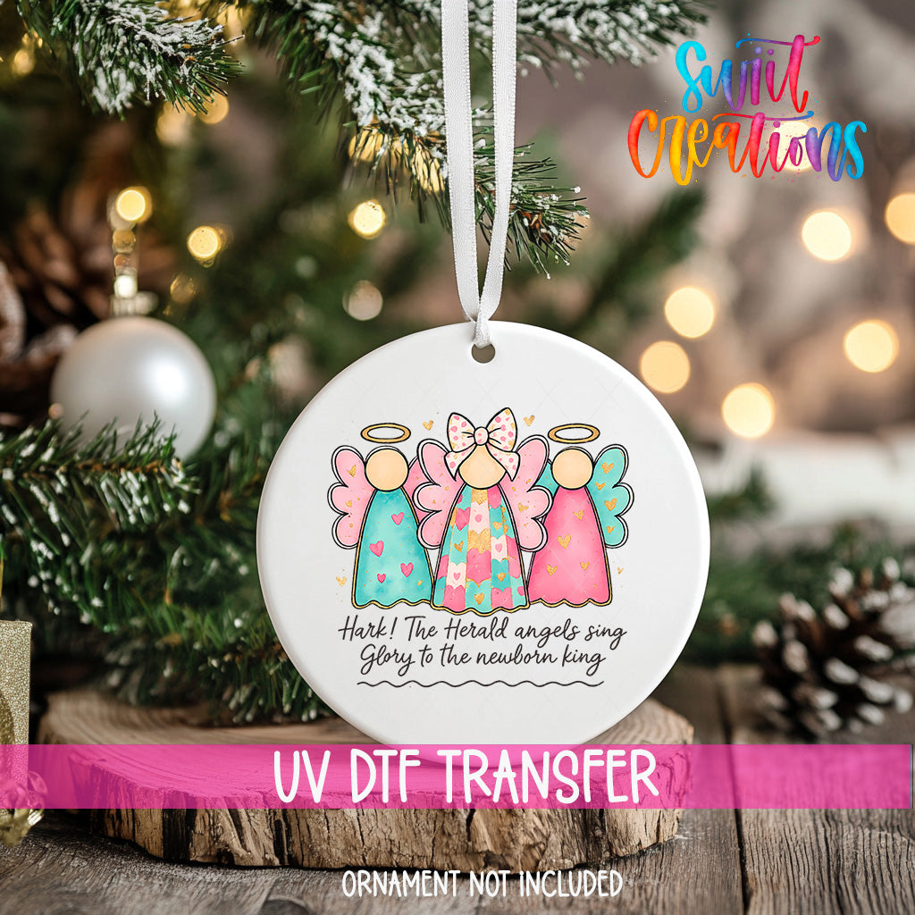 A Christmas tree ornament with three angelic figures and a text message, hanging on a tree branch.