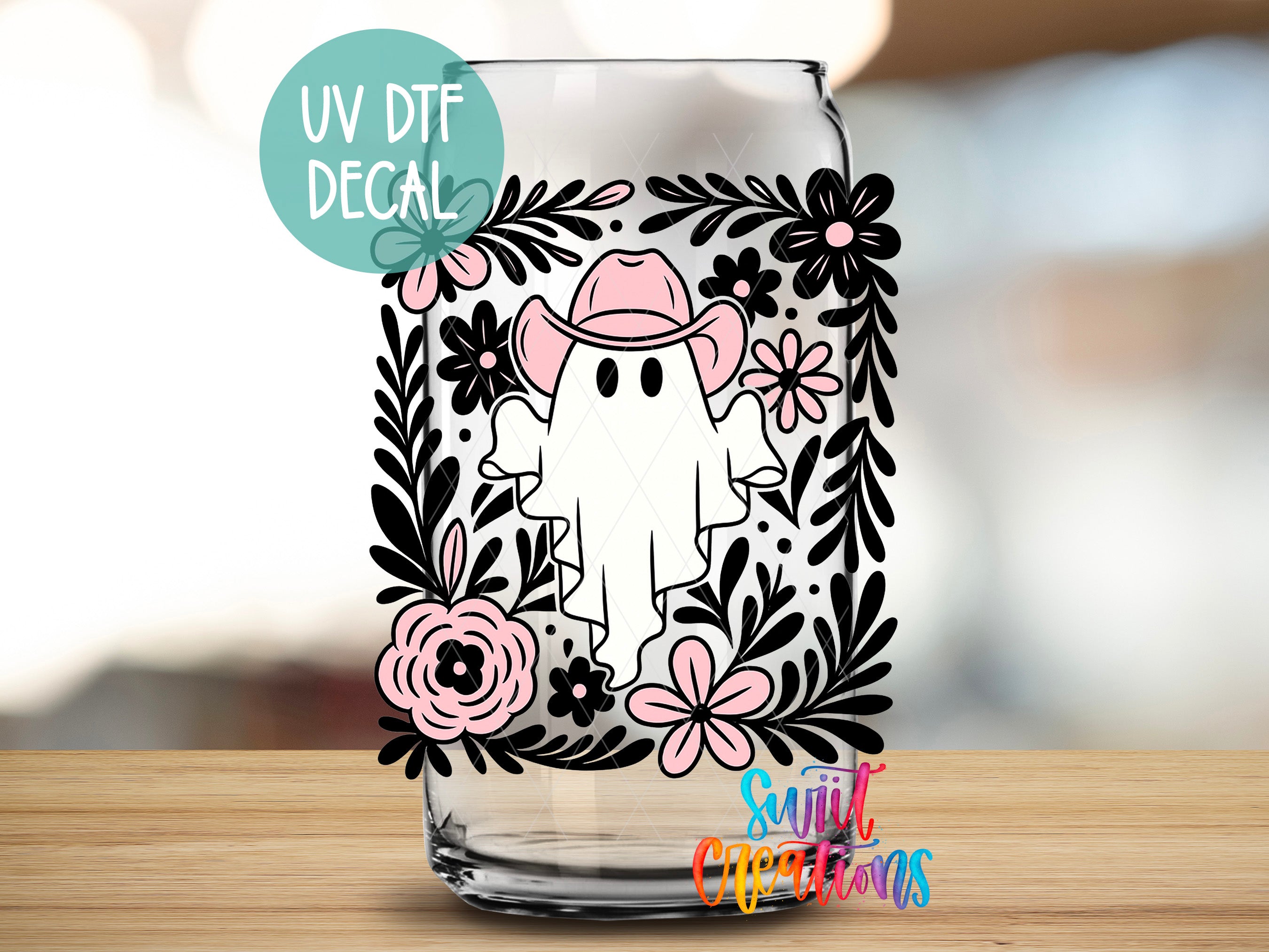 A glass with a decorative decal featuring a ghost wearing a cowboy hat and surrounded by floral elements.