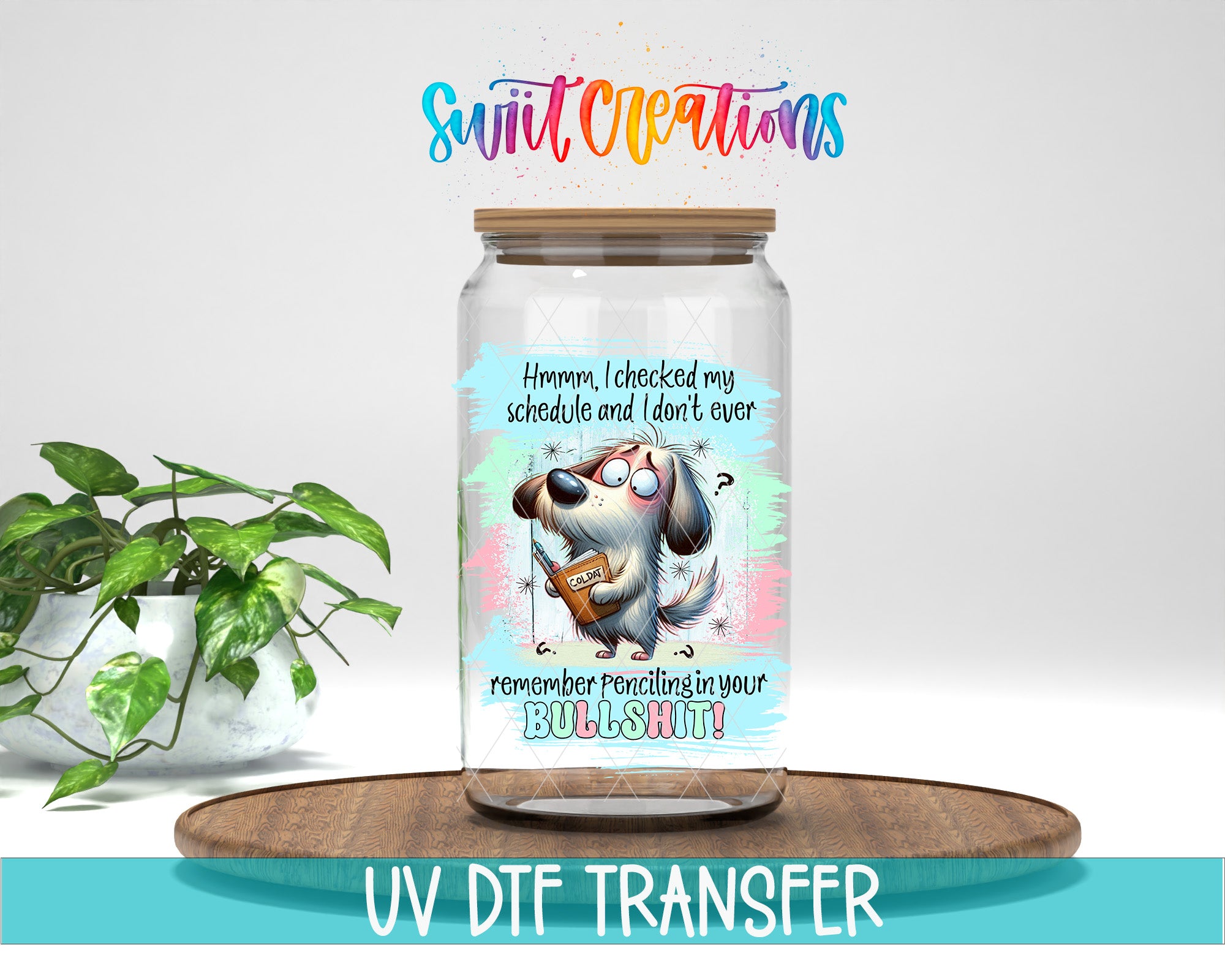 A glass jar with a cartoon dog and text on it, placed on a wooden surface next to a potted plant.