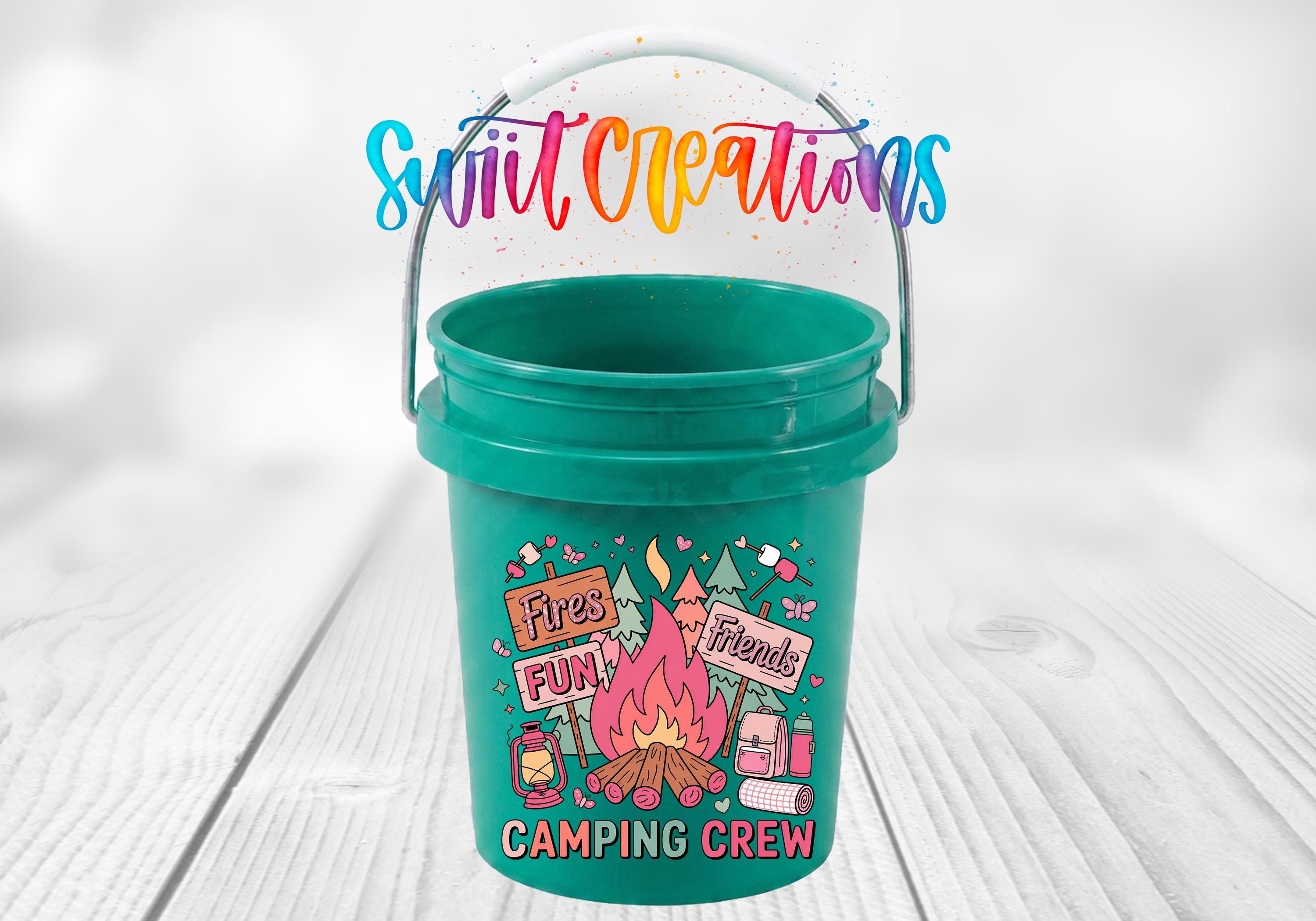 A green bucket with a colorful design featuring camping-related elements, such as a campfire, tent, and camping supplies, along with the text "Camping Crew" and "Fires Fun! Friends".