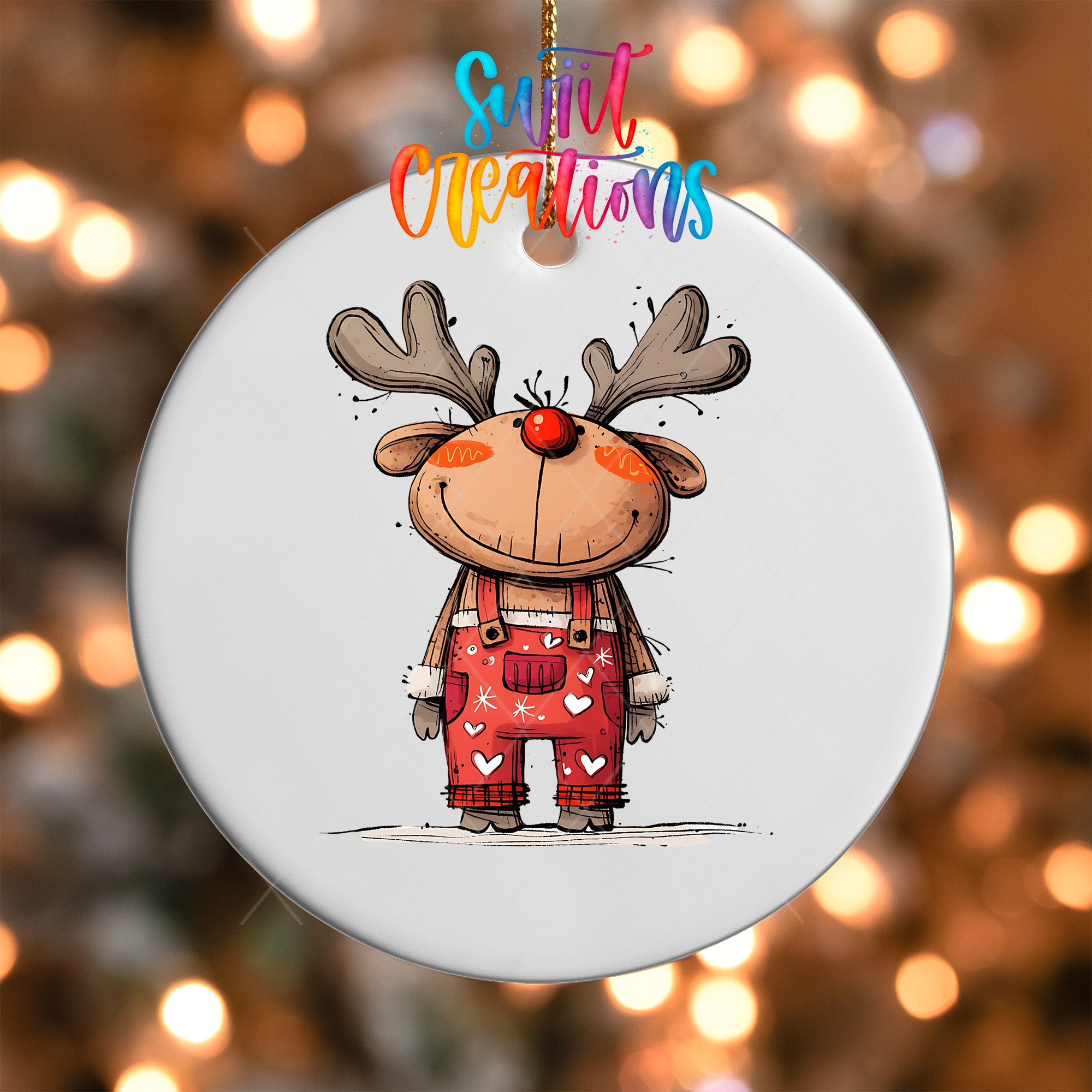 A white ornament featuring a cartoon reindeer wearing overalls with hearts on them, hanging against a background of colorful lights.