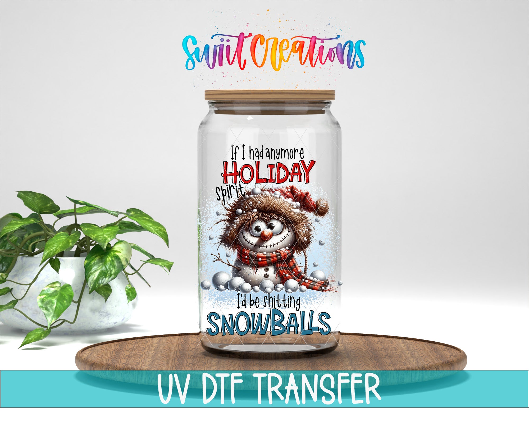 A glass jar with a snowman design and the text "If I had anymore HOLD onto SPIRIT" printed on it, placed on a wooden surface next to a potted plant.