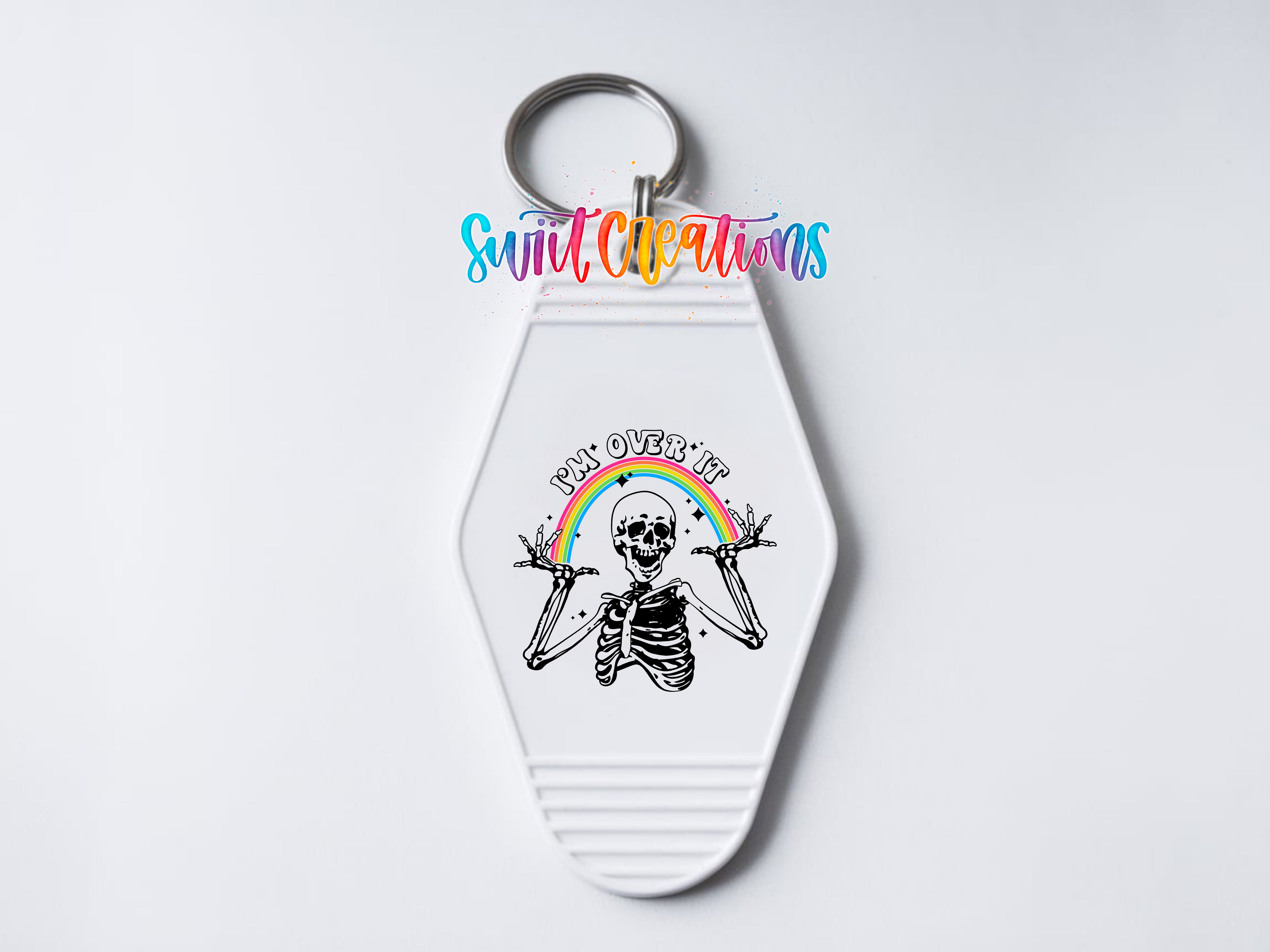 A white keychain with a skeleton graphic and a rainbow graphic.