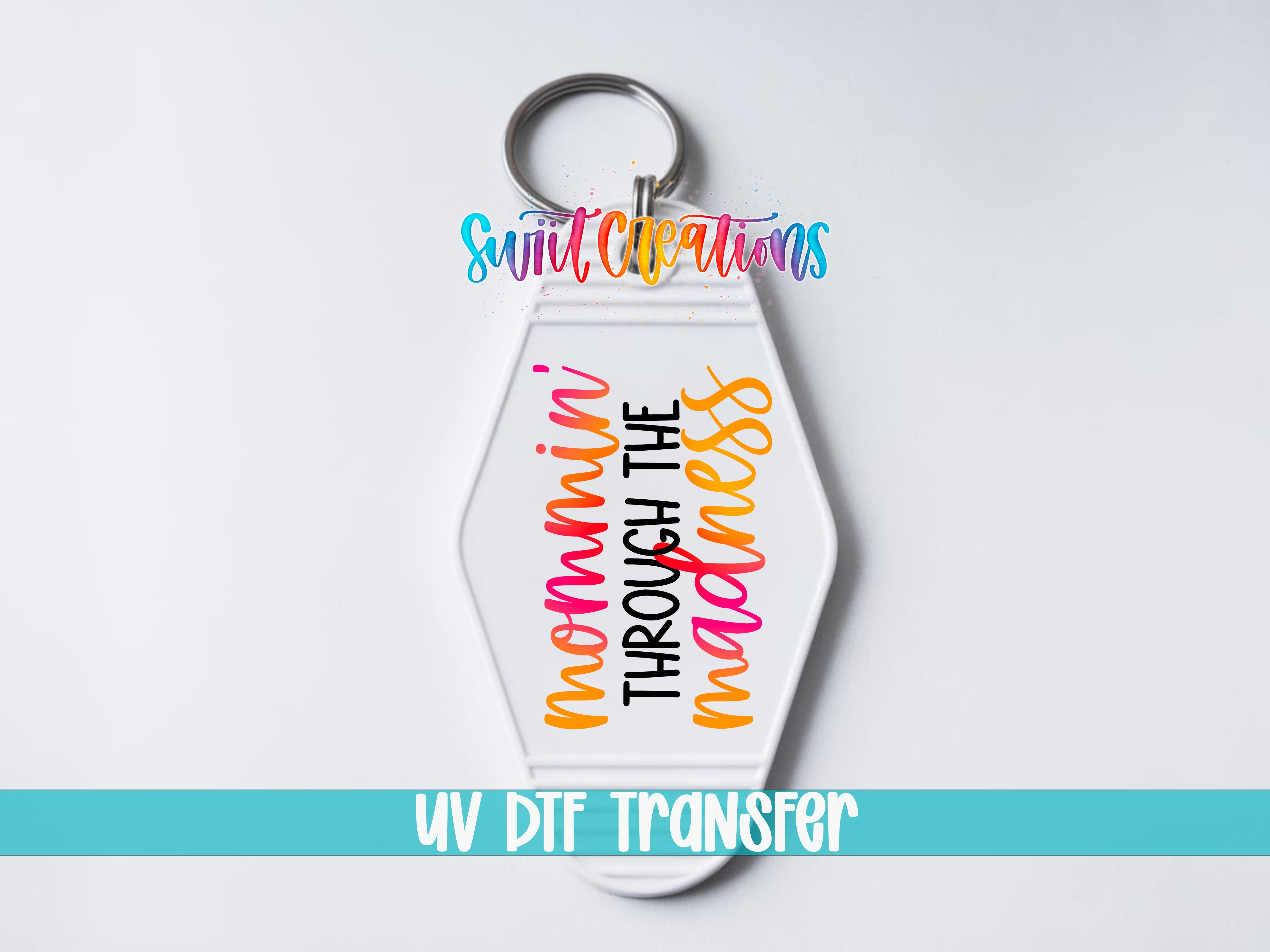 A keychain with a colorful, hand-lettered message that says " mommy through the madness" in a stylized font.
