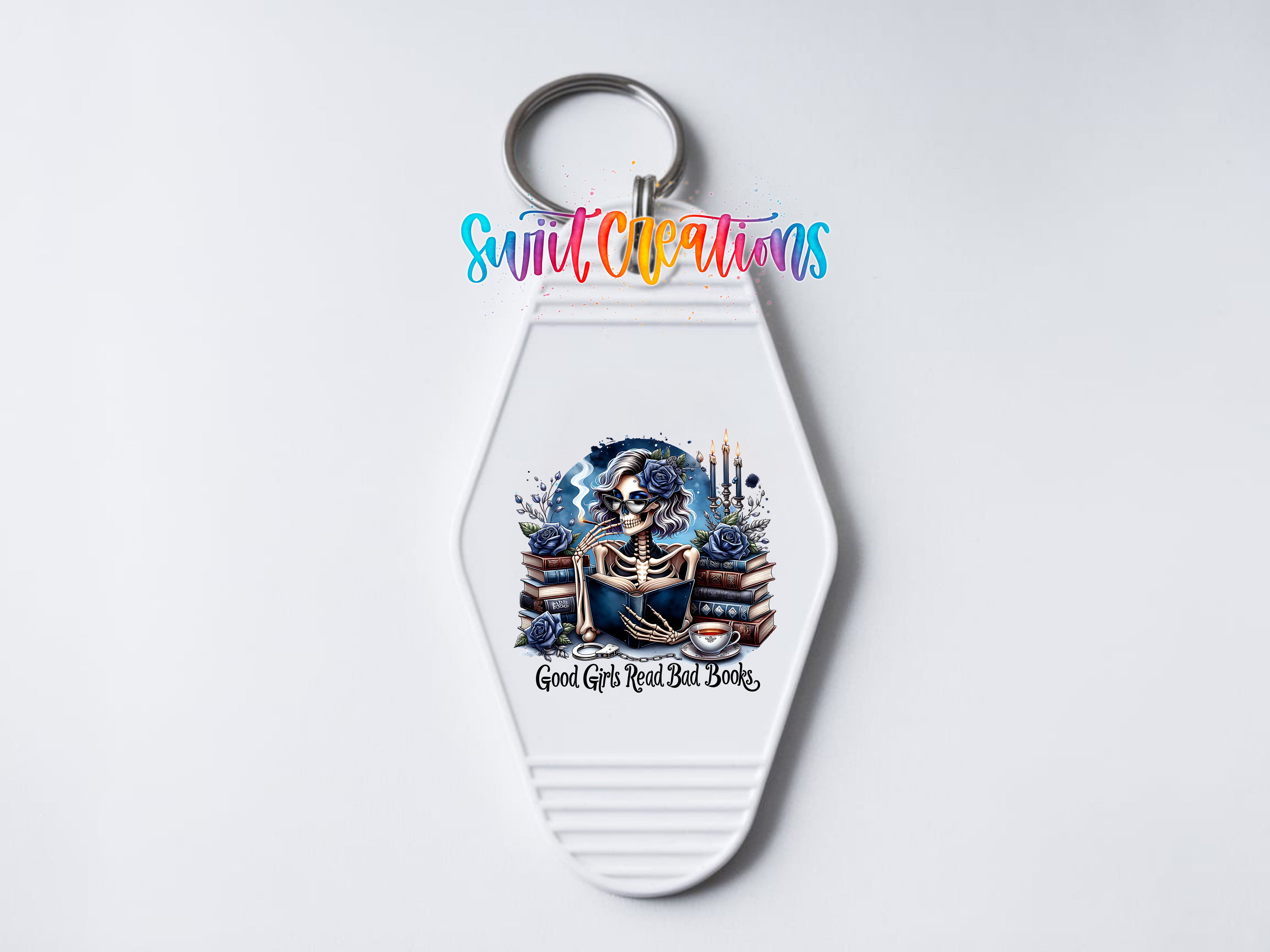 A keychain with a colorful design featuring a skeleton surrounded by books and flowers, with the text "Good Girls Read Bad Books" printed on it.