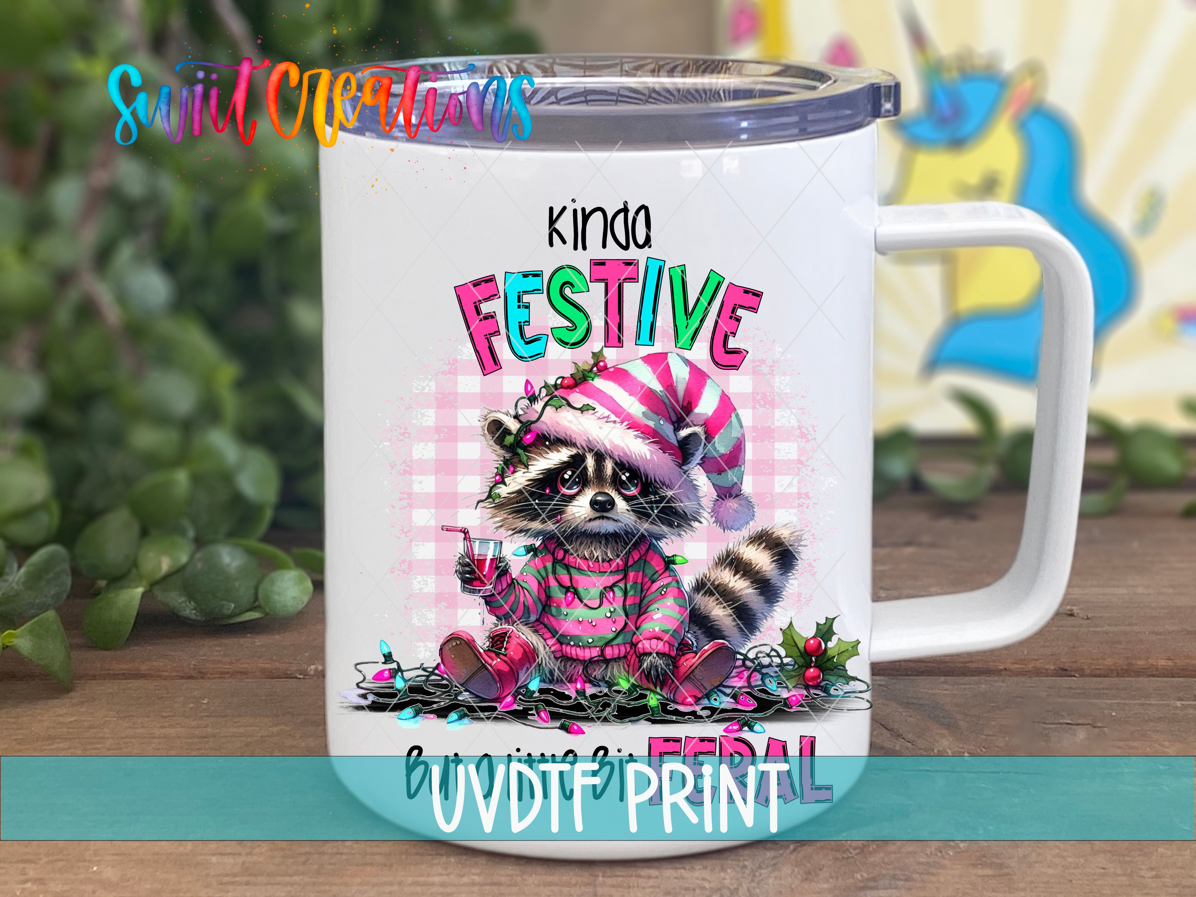 A white mug with a colorful illustration of a raccoon wearing a festive hat and sweater, sitting on a pile of Christmas lights and ornaments.