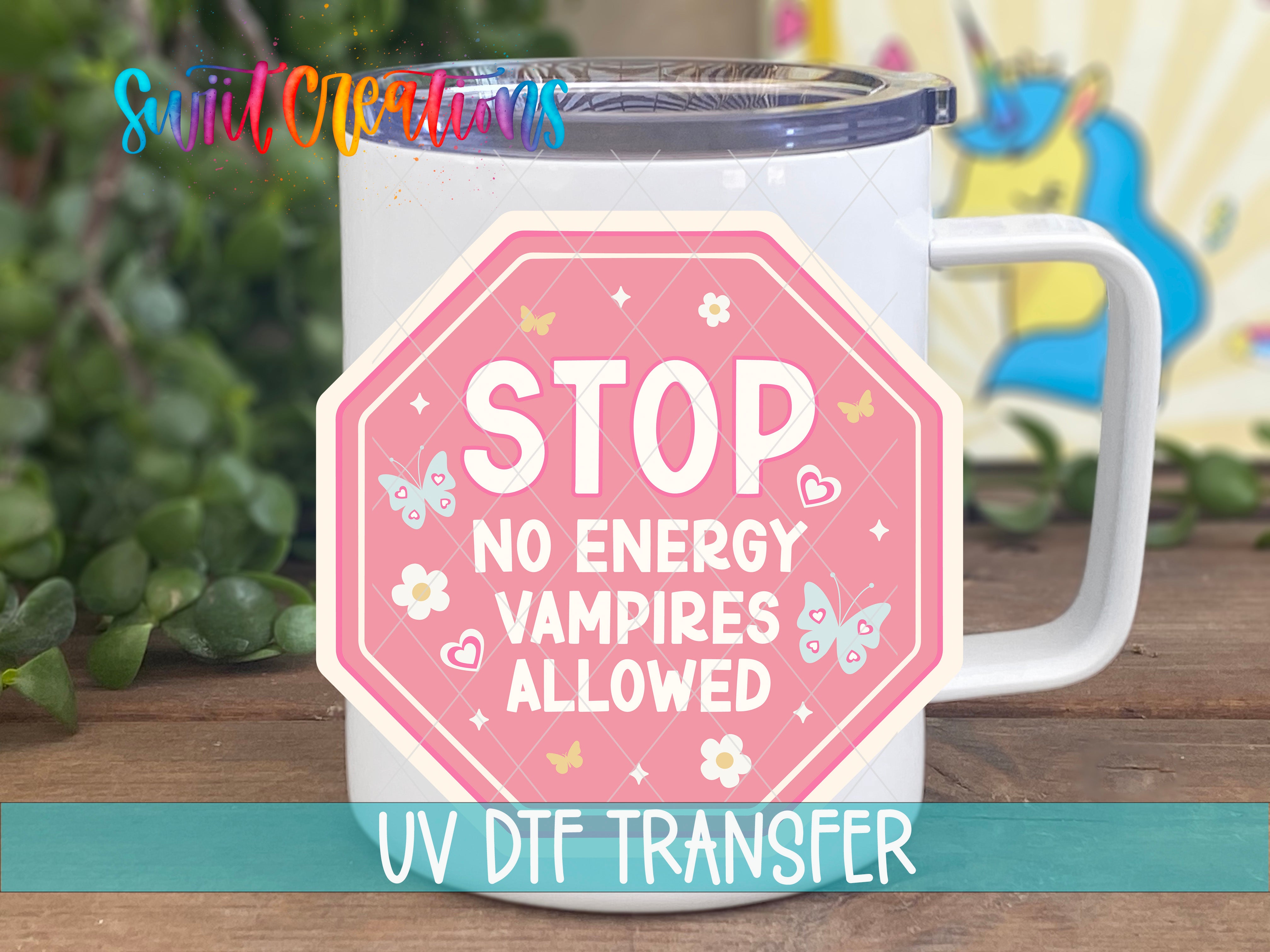 A white mug with a pink and white sticker that says "STOP NO ENERGY VAMPIRE ALLOWED" and "UV DTF TRANSFER".