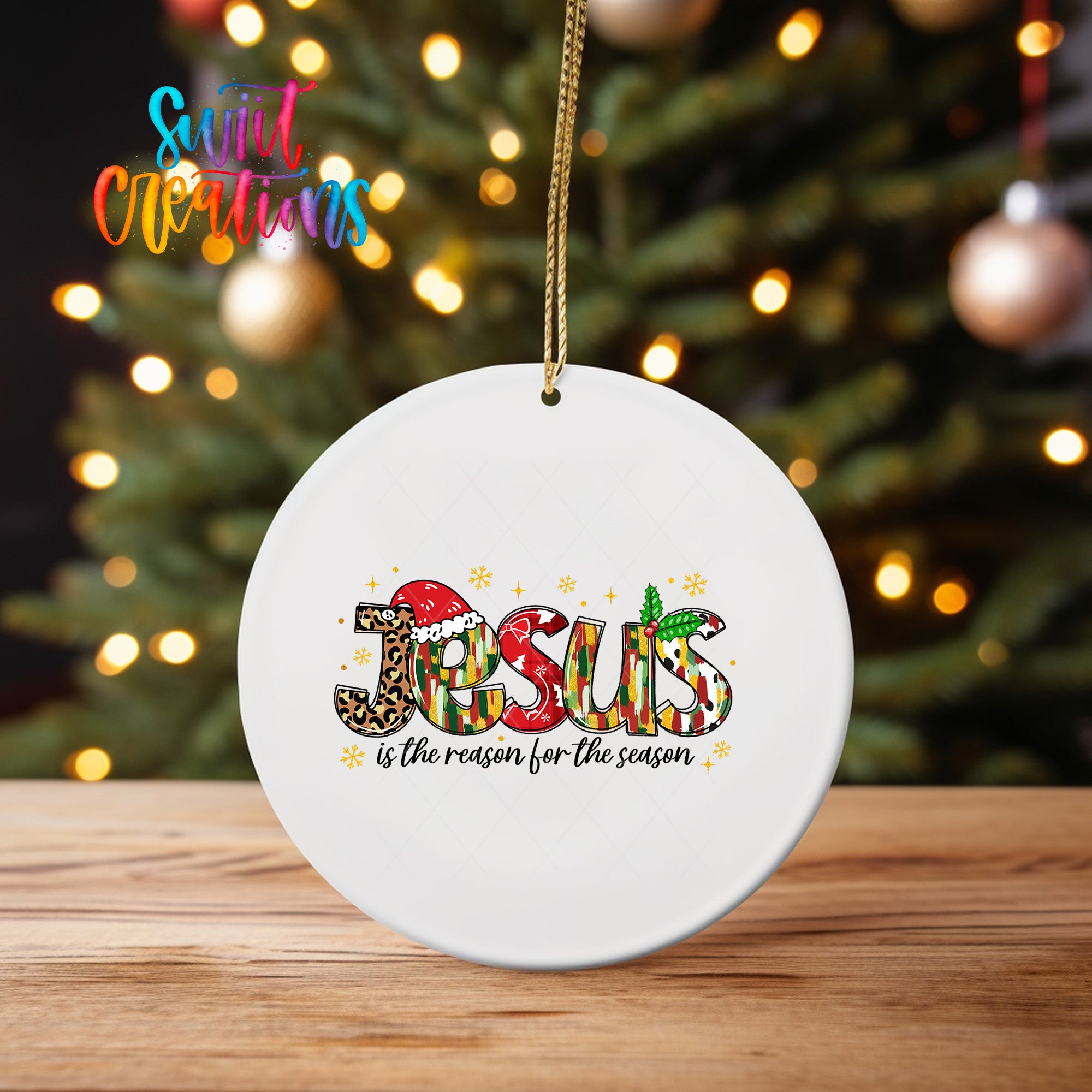 A white ceramic ornament with the word "JESUS" written in a colorful, stylized font, surrounded by decorative elements such as snowflakes and stars.