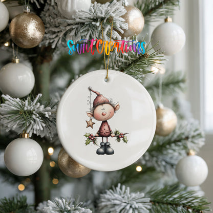 A white ceramic ornament with a cartoon elf design hangs from a Christmas tree, surrounded by white and gold ornaments.