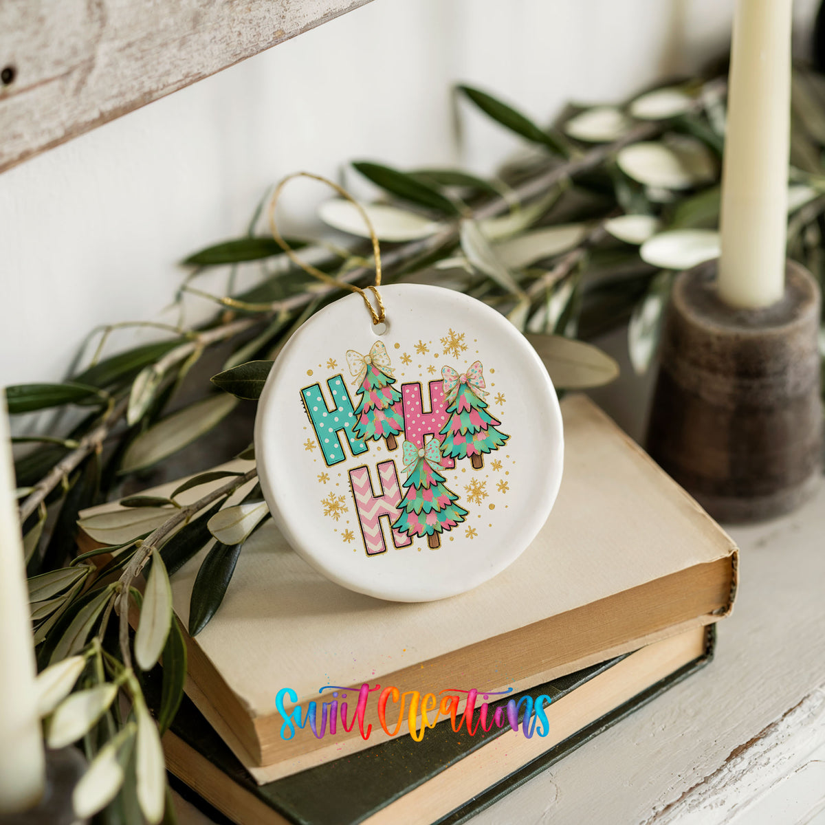 A white ceramic ornament with the word "HAPPY" written on it, surrounded by colorful Christmas trees and decorations, placed on top of a stack of books.