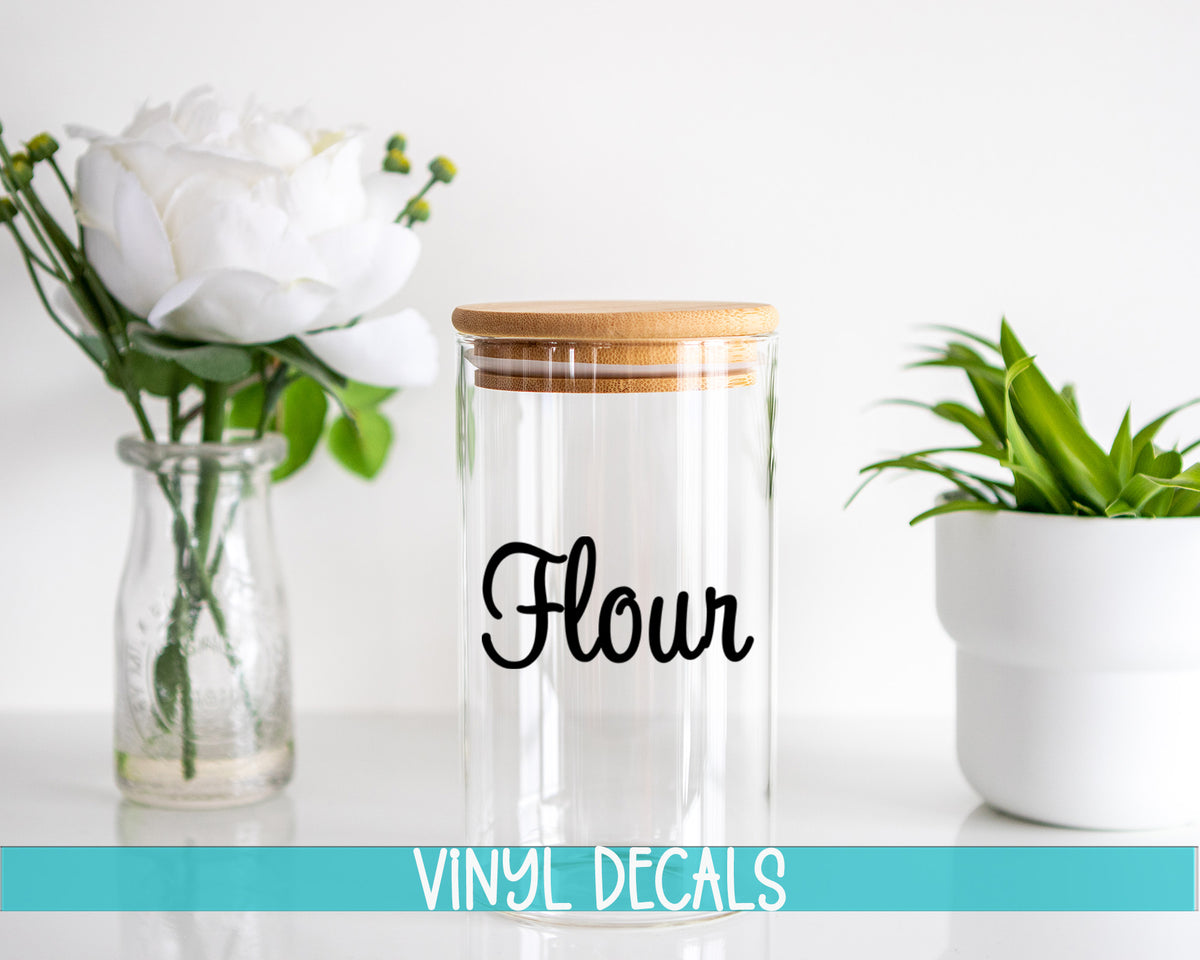 a glass jar with a wooden lid and a flower in a vase