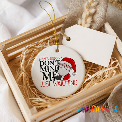 A white ceramic ornament with a humorous text design, placed in a wooden crate surrounded by straw.