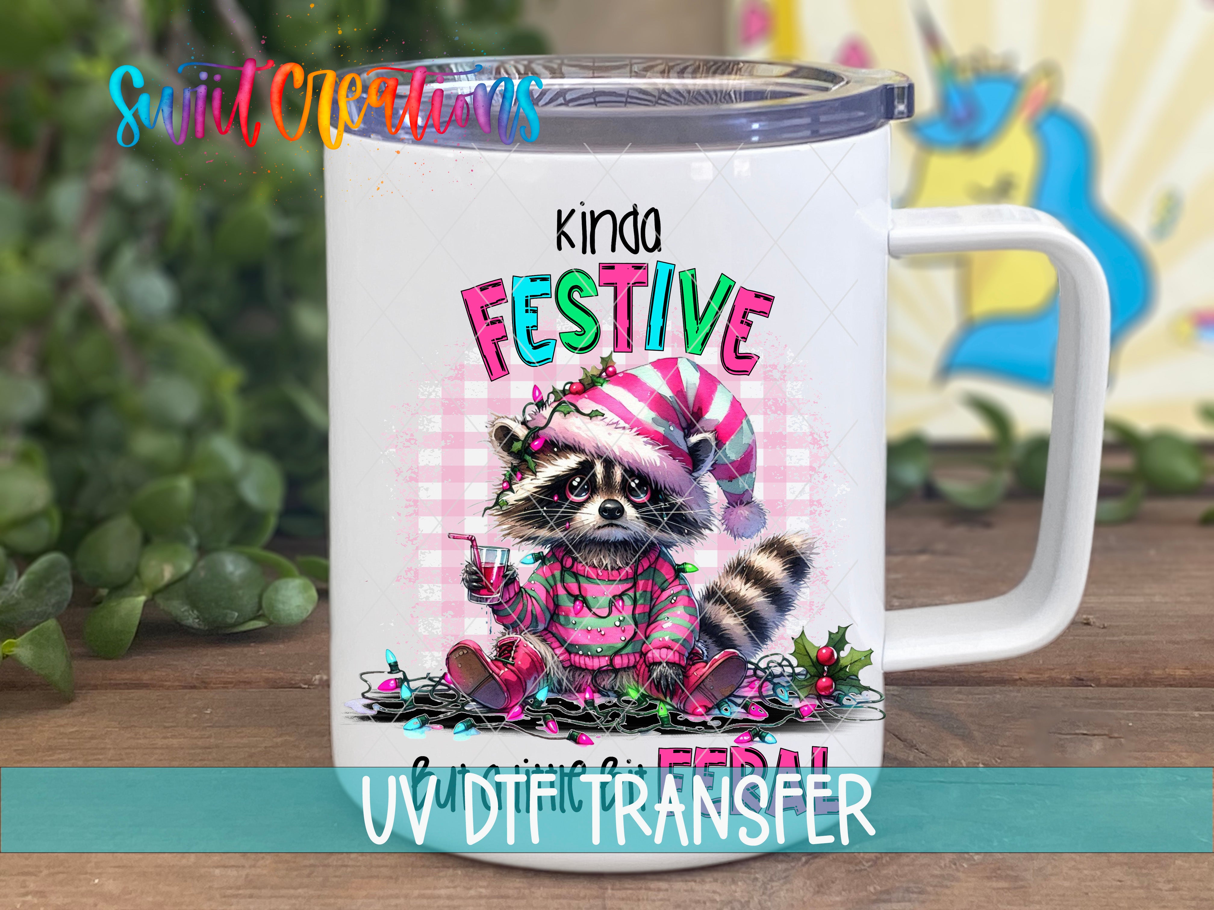 A white mug with a colorful illustration of a raccoon wearing a festive hat and sweater, sitting on a pile of Christmas lights and ornaments.