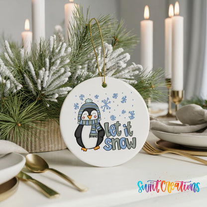 A white ornament with a penguin and snowflakes, along with the text "Let it snow" is displayed on a table.
