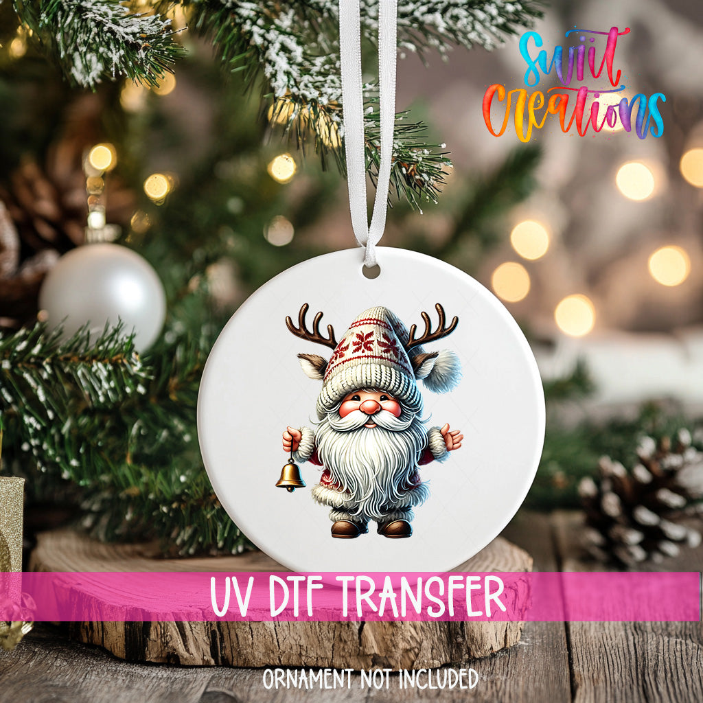 A white ornament with a gnome-like figure wearing a hat and holding a bell, hanging on a Christmas tree.