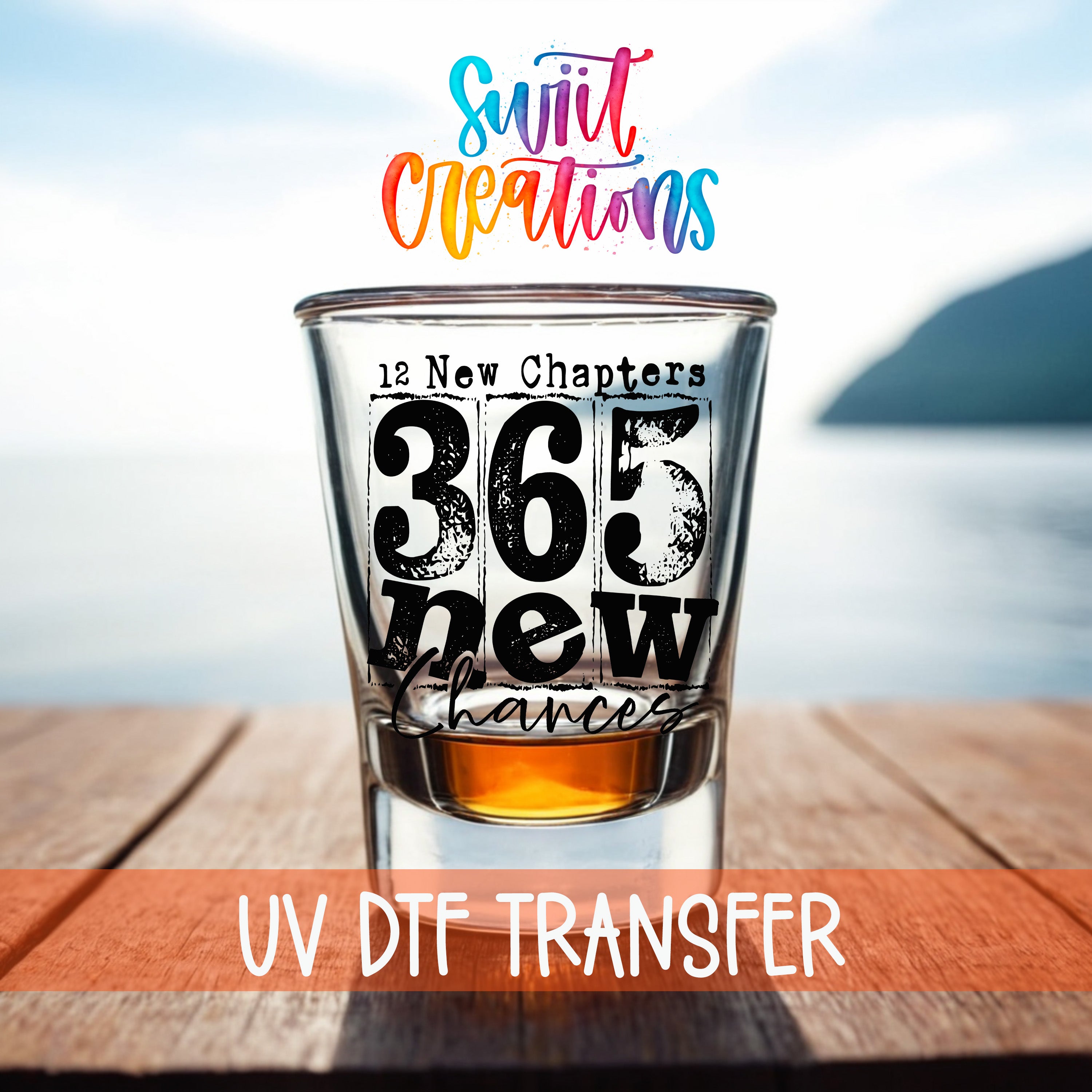 a shot glass with the text "365 New Chapters" printed on it, placed on a wooden surface with a body of water in the background.