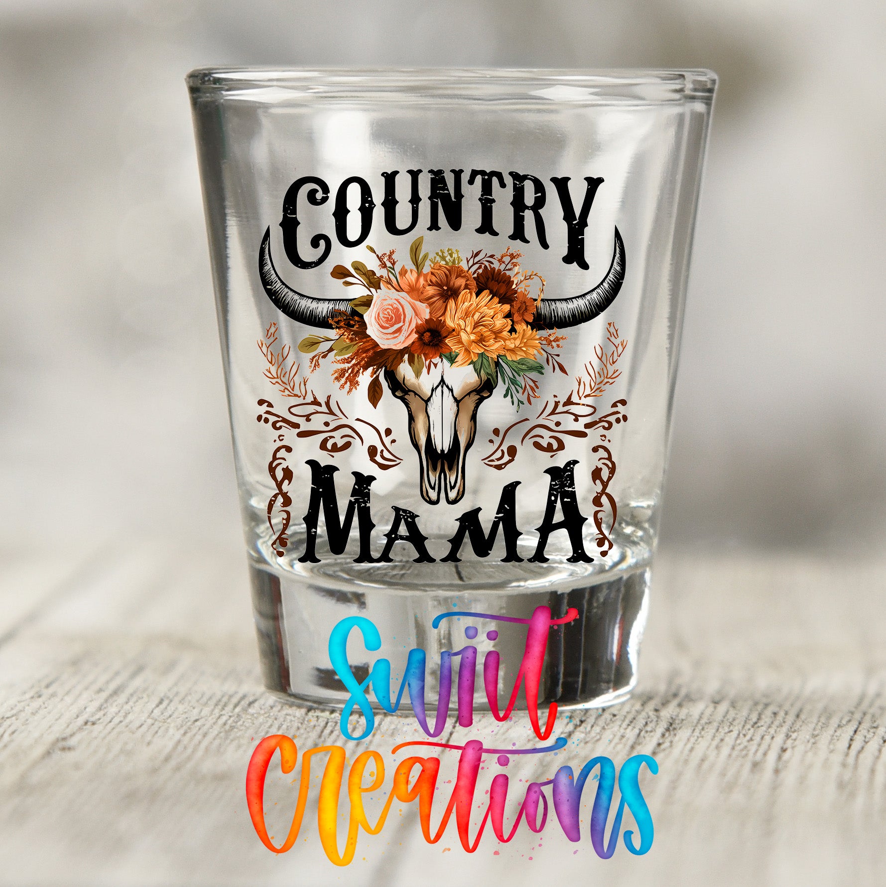 A shot glass with a floral design and the text "Country Mama" printed on it.