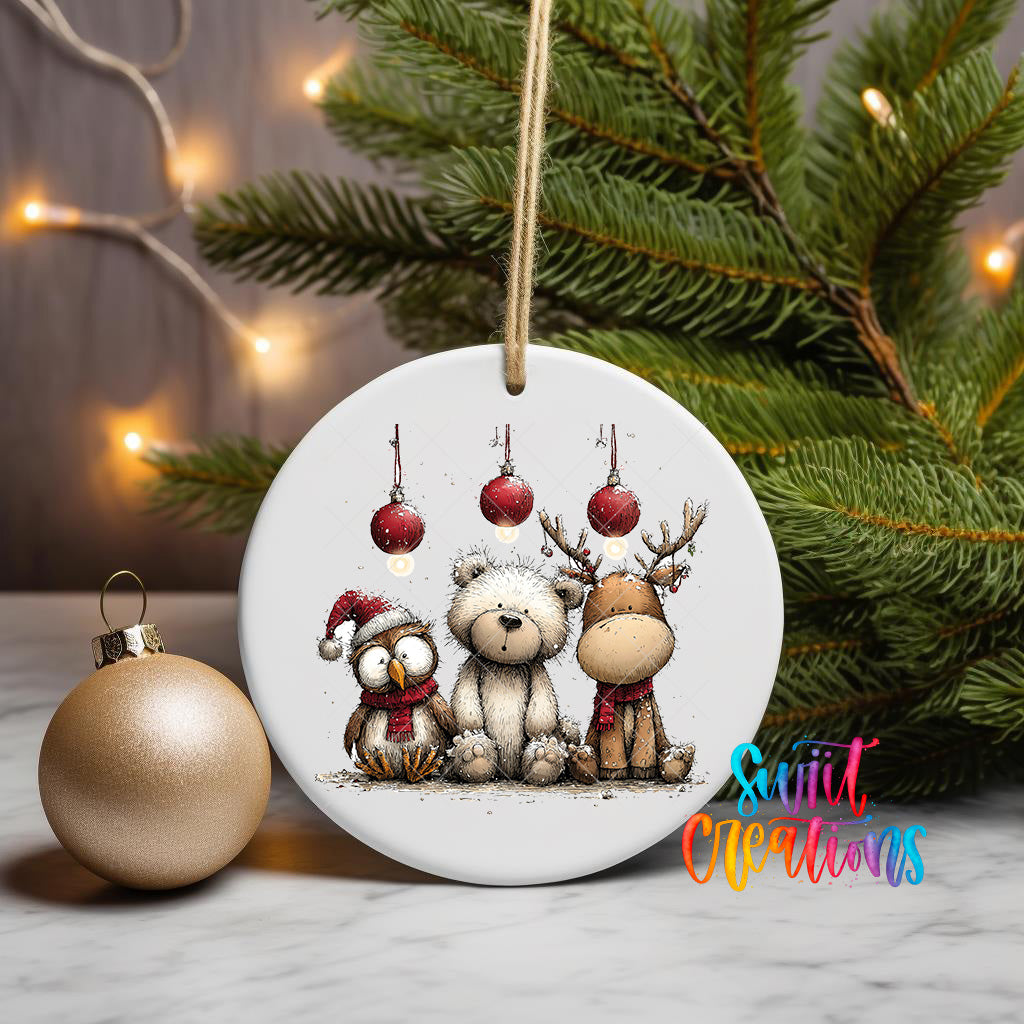A white ceramic ornament featuring a teddy bear, reindeer, and owl, along with Christmas lights and ornaments, is displayed on a table.
