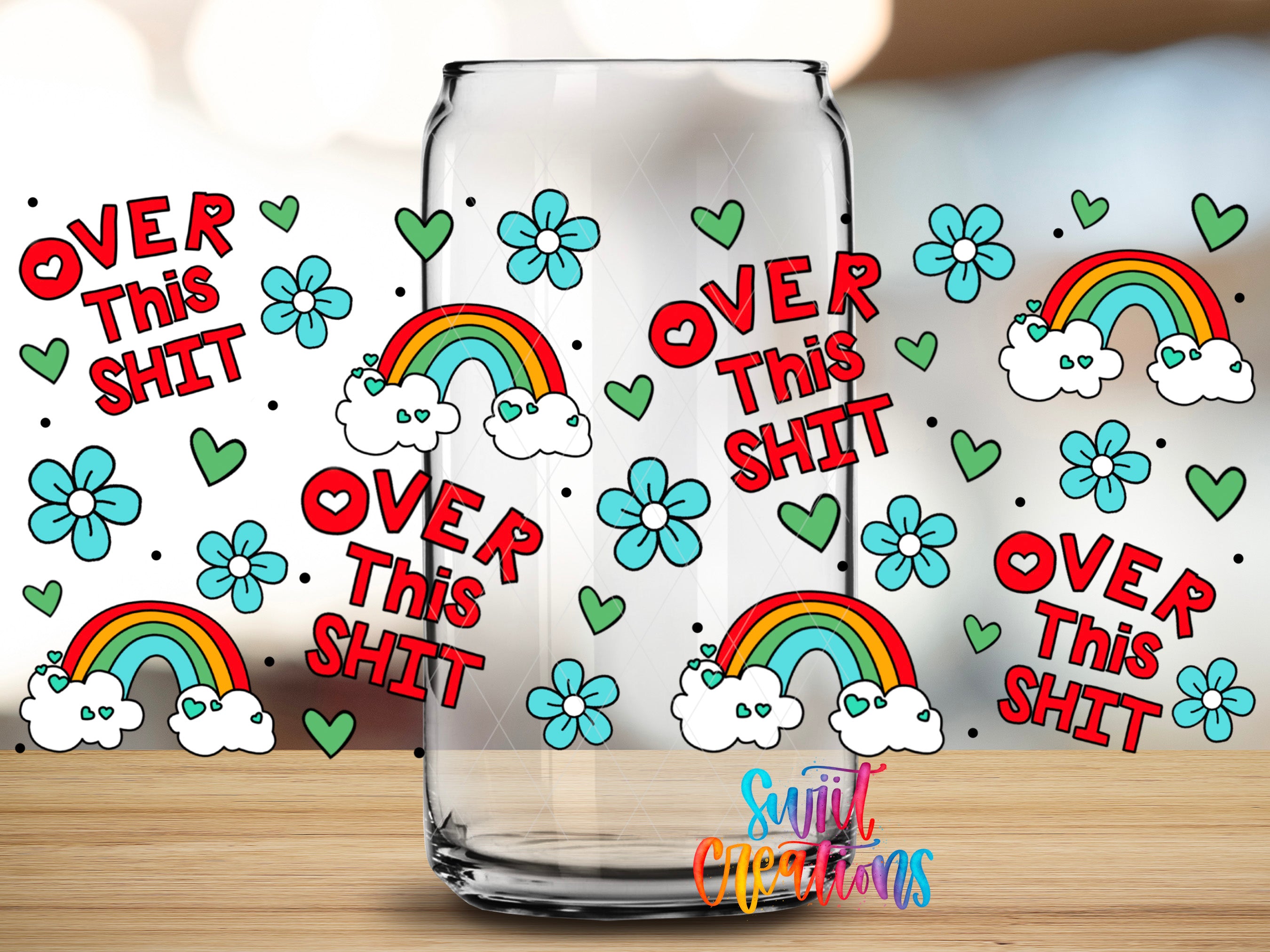 a glass with a colorful and whimsical design, including rainbows, flowers, and the text "OVER This shit" repeated multiple times.