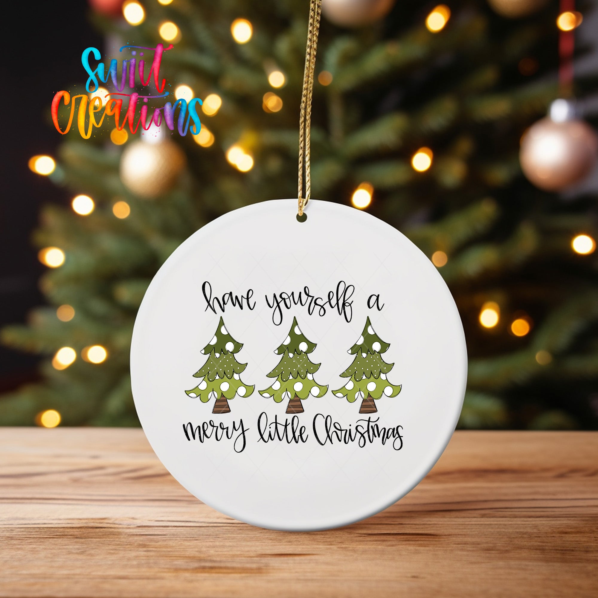 A white ceramic ornament with a Christmas tree design and the text "Have yourself a merry little Christmas" hanging from a string.