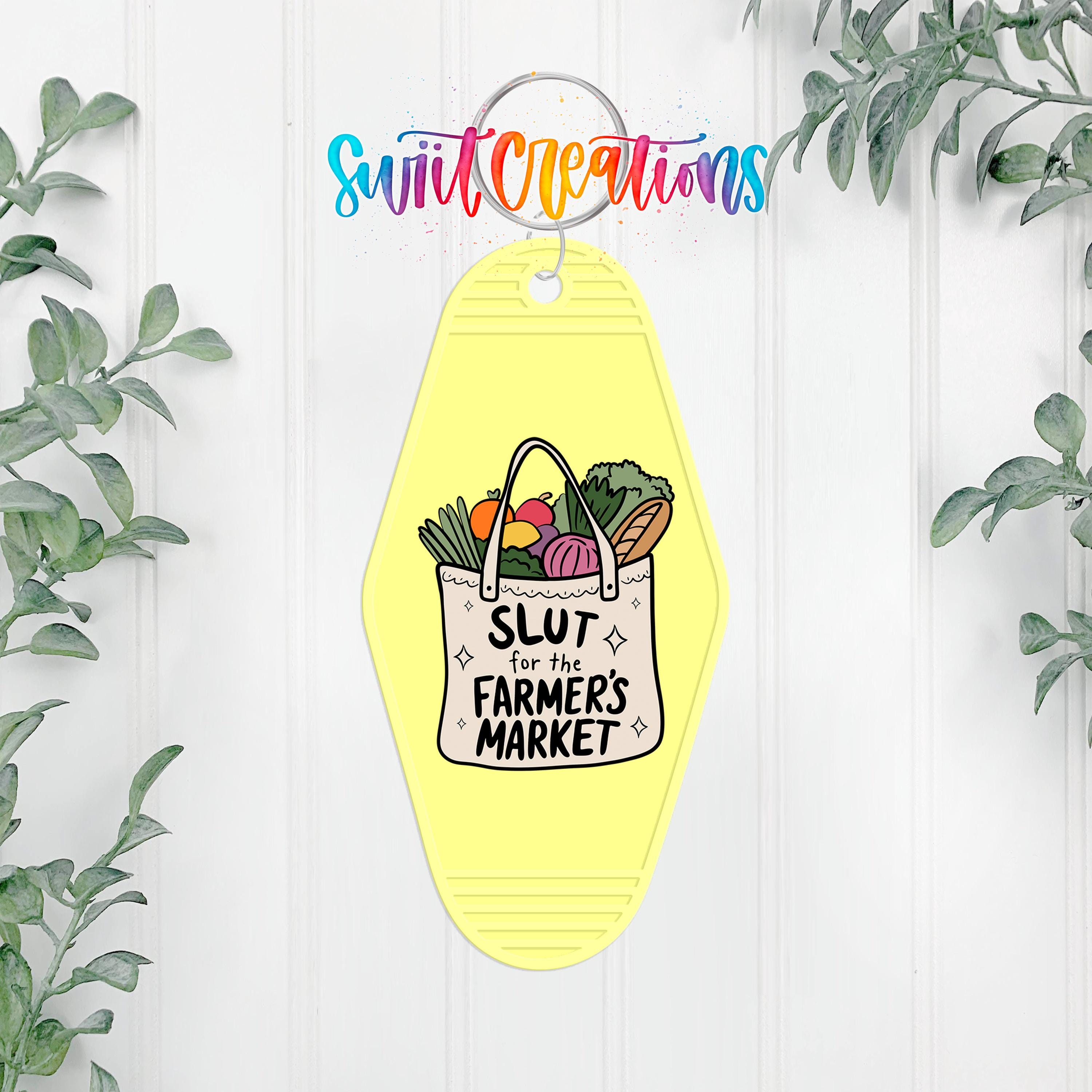 A yellow keychain with a bag of vegetables hanging on a wall, surrounded by greenery.
