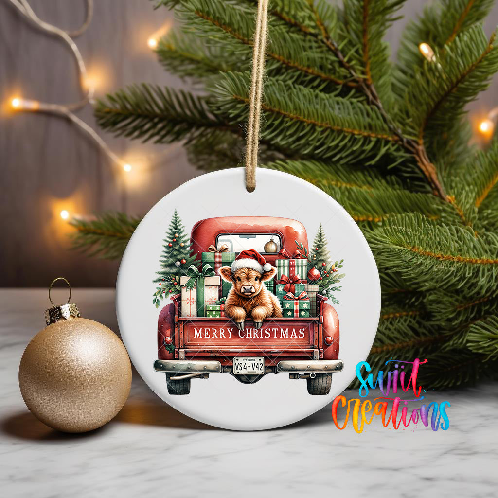 A white ceramic ornament featuring a red truck with a bear and Christmas presents in the back, surrounded by greenery and twinkling lights.