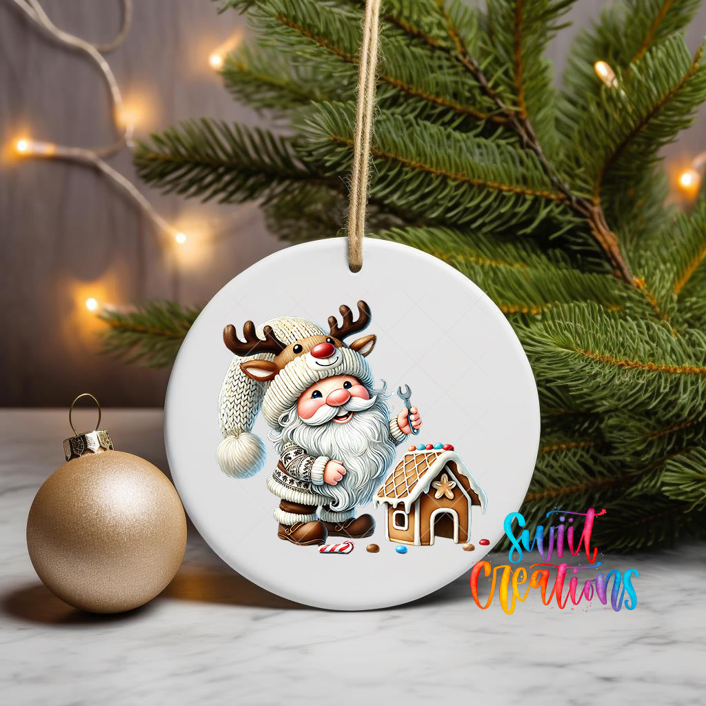 A white ceramic ornament featuring a Santa Claus figure with antlers and a gingerbread house, surrounded by Christmas lights and greenery.