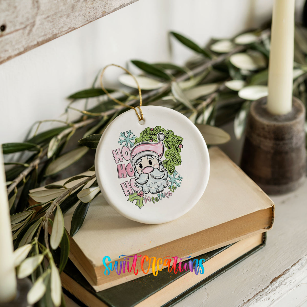 A ceramic ornament with a Santa Claus design, featuring a snowflake and the text "HOOK HOOK" is placed on top of a stack of books.