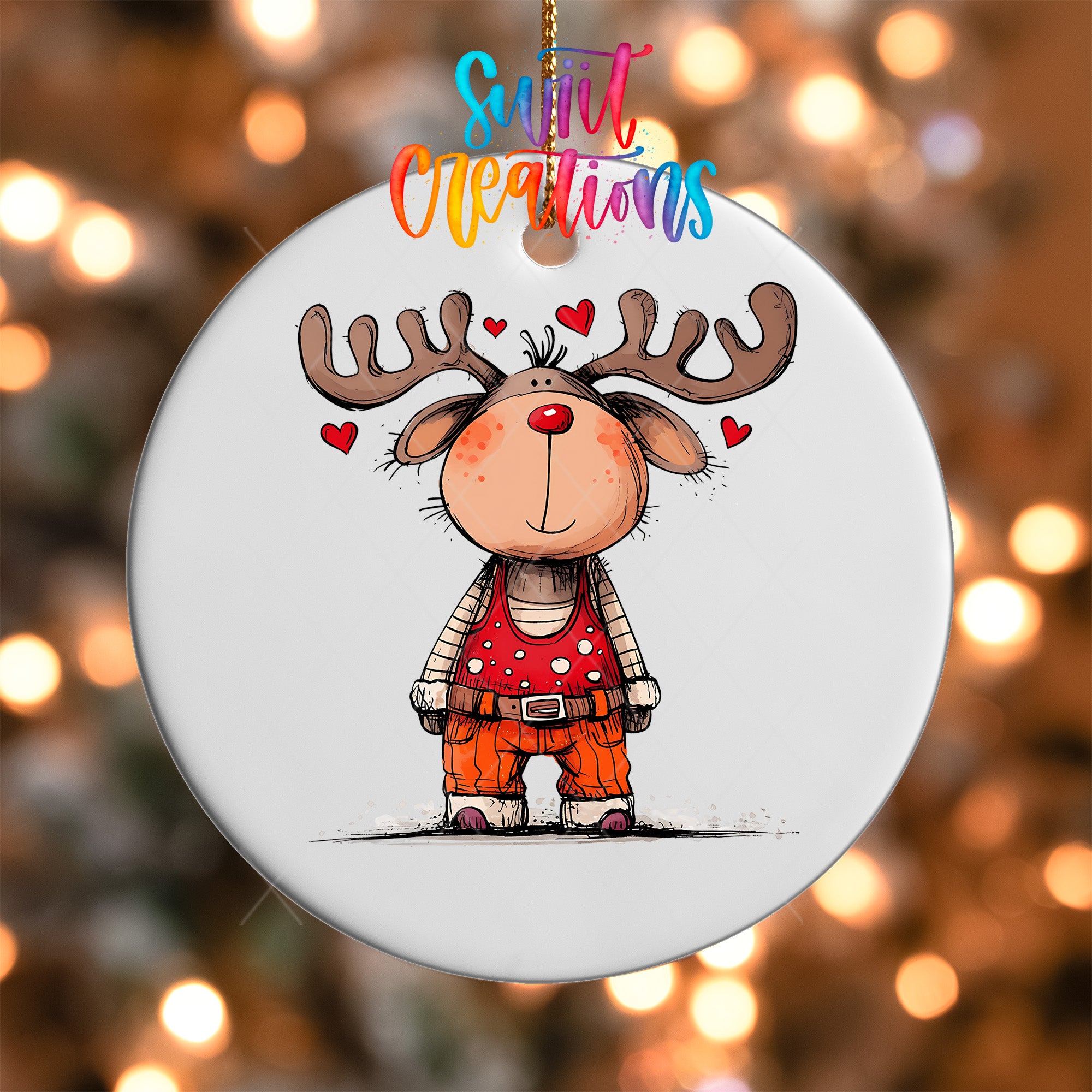 A white ornament with a cartoon reindeer wearing a red shirt and orange pants, surrounded by hearts, hanging against a background of colorful lights.