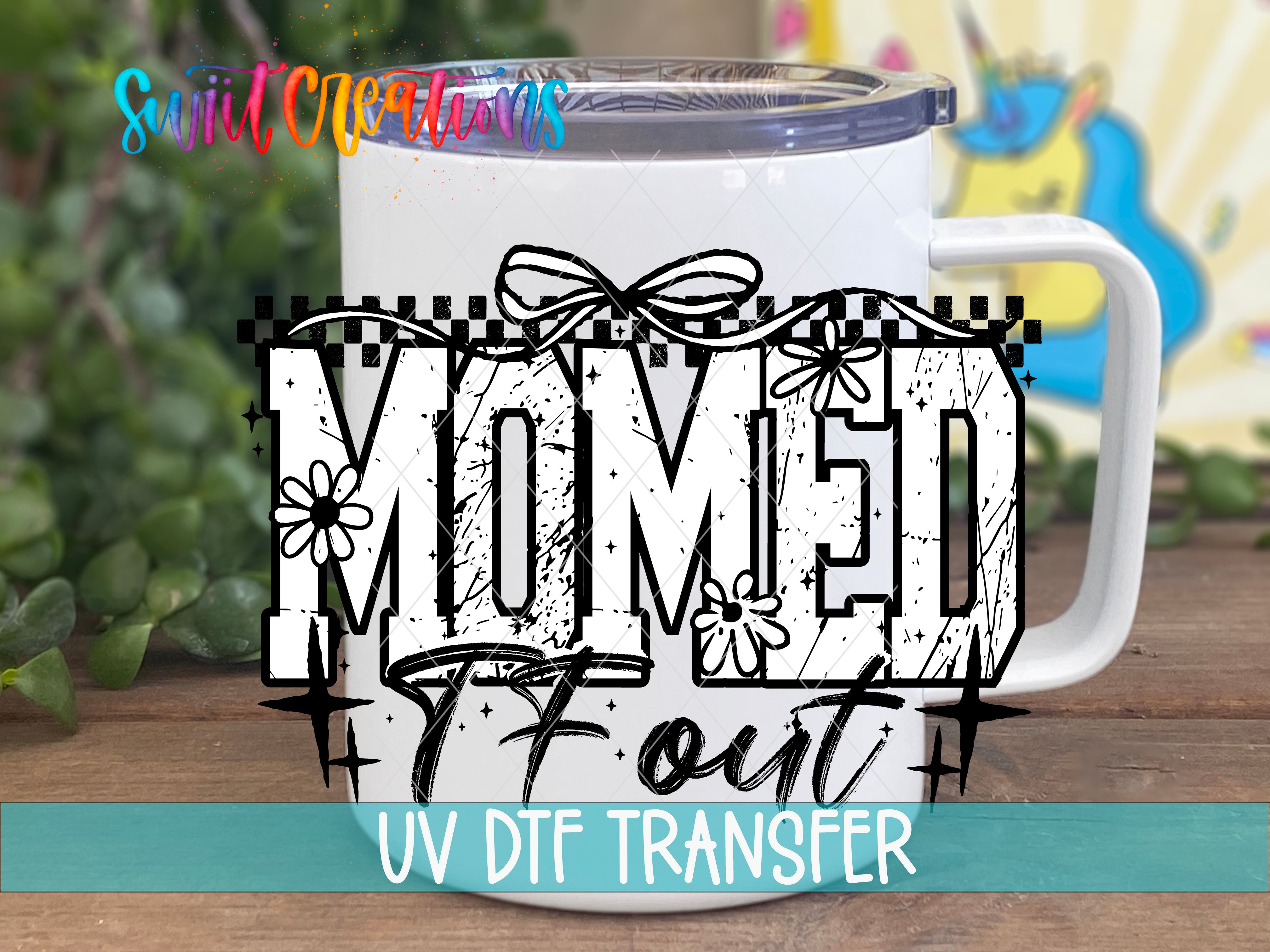 A white mug with a printed design on it, along with text that says "MOMED 7 OUT" and "UV DFT TRANSFER".