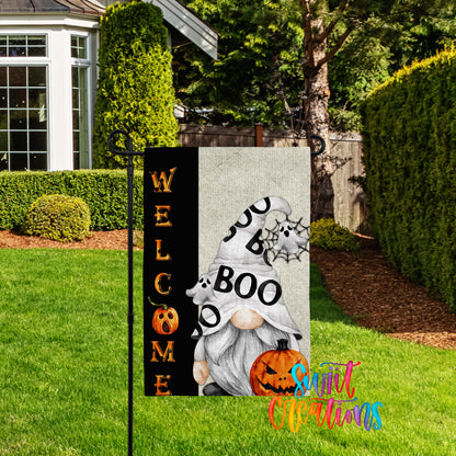 A Halloween-themed garden sign featuring a gnome holding a pumpkin and the text "WELCOME BOO"