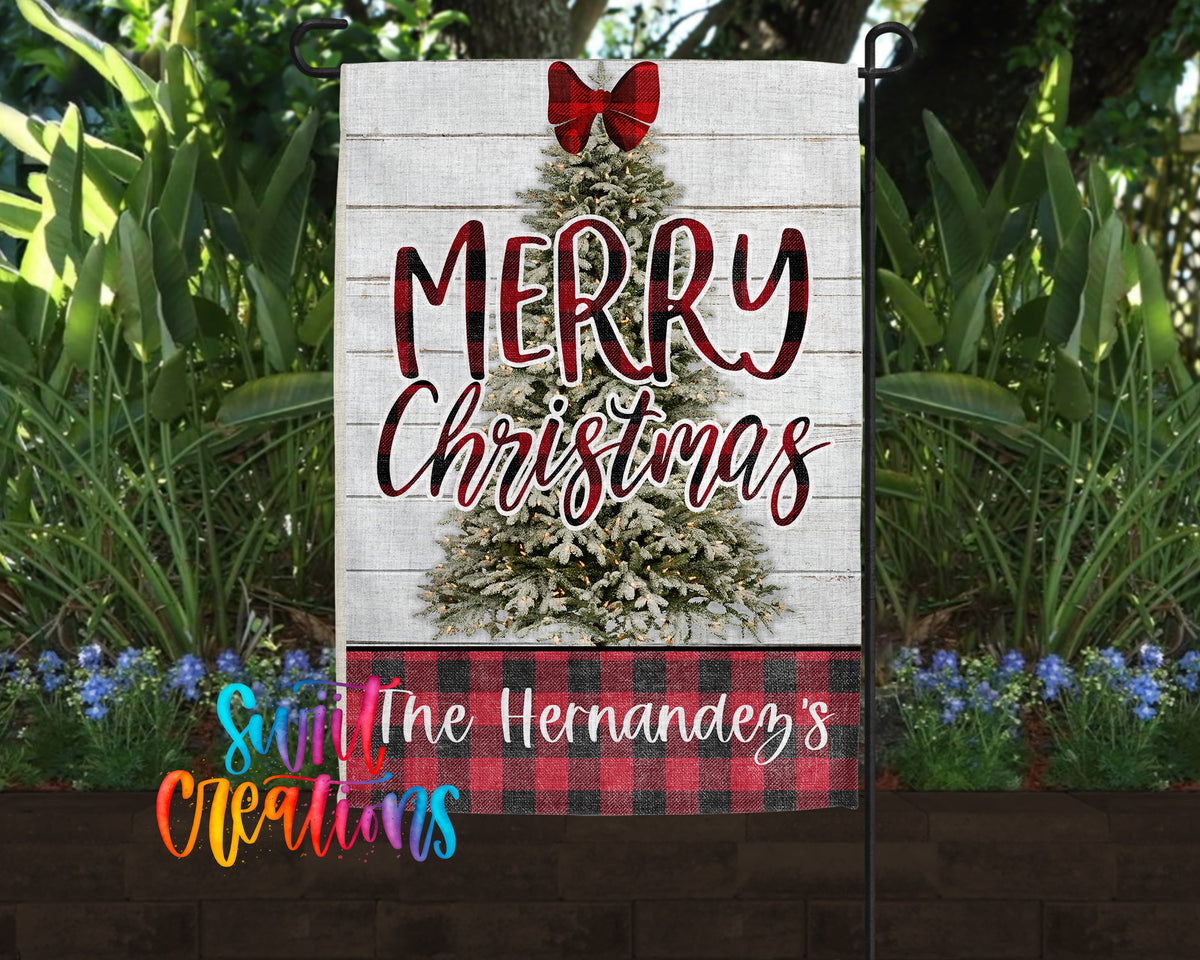 A white garden sign with a red bow and the text "MERRY CHRISTMAS" displayed on it, surrounded by greenery and flowers.