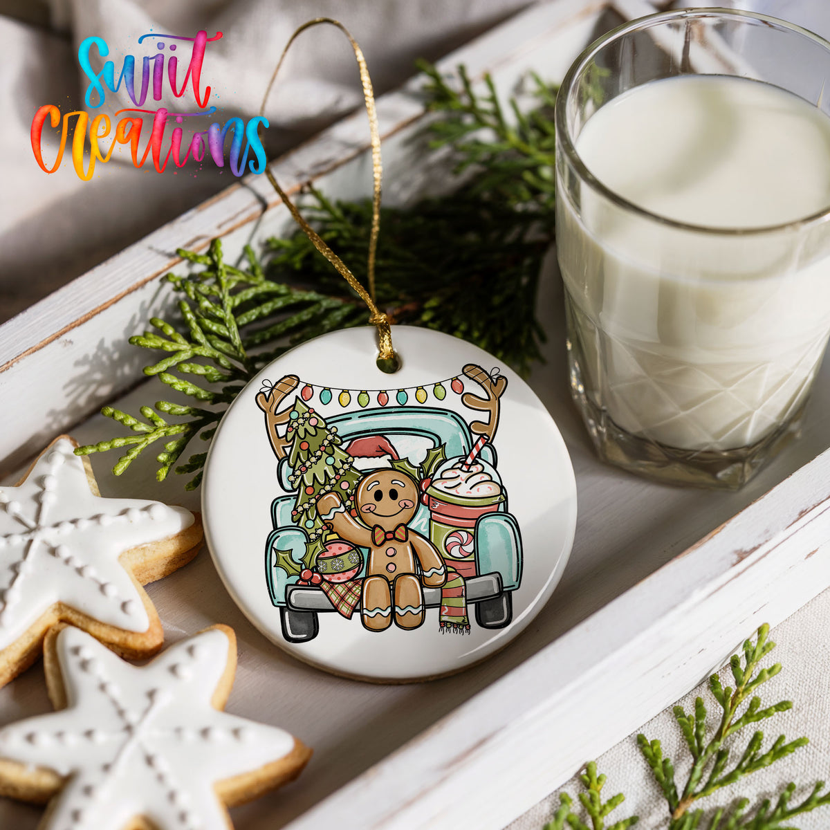 a Christmas ornament with a gingerbread man and a truck, along with a glass of milk and some cookies.