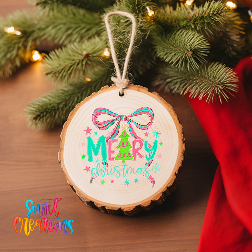 A round wooden ornament with a bow and the text "Merry Christmas" is hanging on a Christmas tree, surrounded by pine branches and twinkling lights.