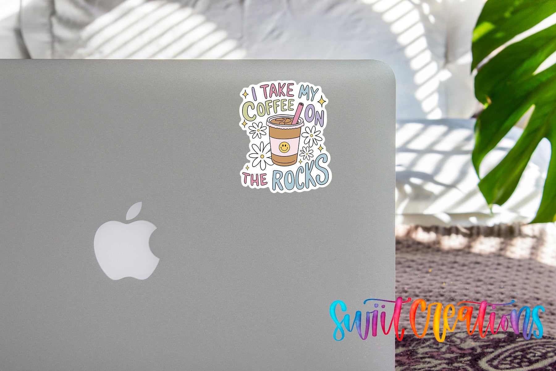 a sticker on the back of a silver laptop with a coffee cup and the text "I take my coffee on the rocks".