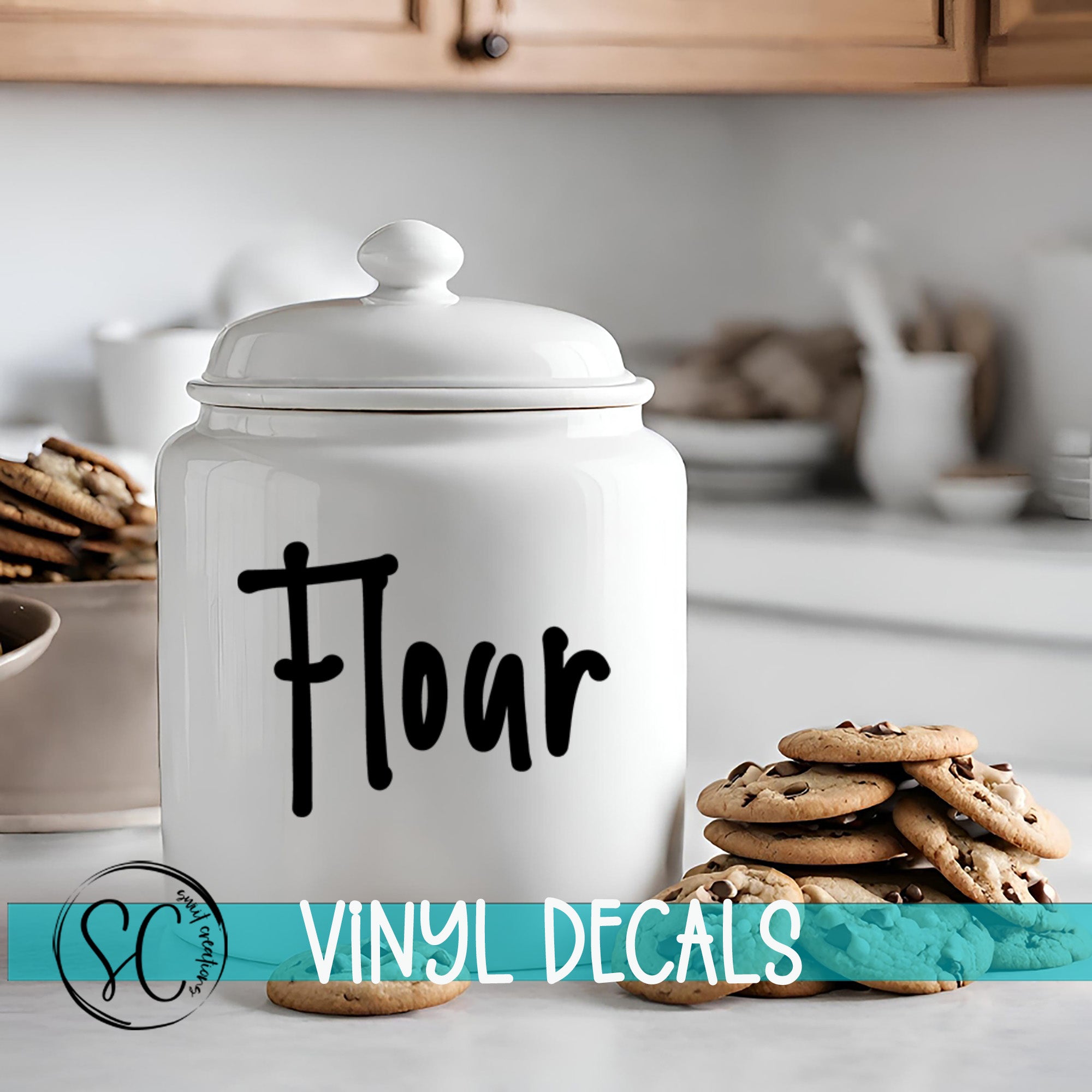 A white ceramic jar with the word "Flour" printed on it, placed on a kitchen counter next to a stack of chocolate chip cookies.