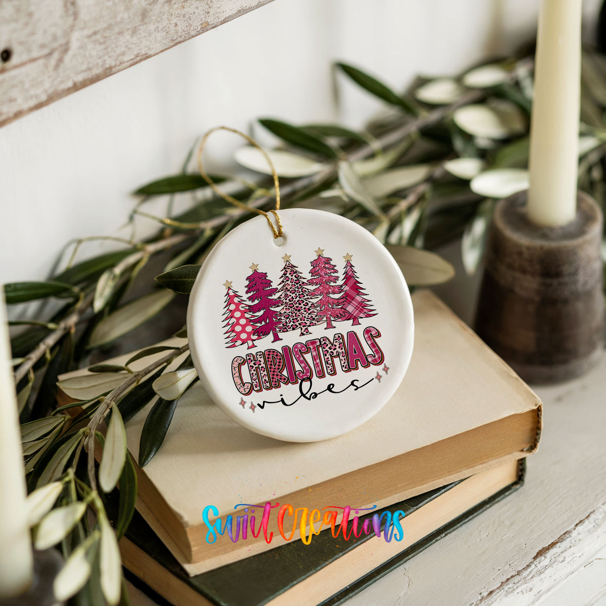 A white ceramic ornament with a Christmas tree design and the text "Christmas vibes" is placed on top of a stack of books.