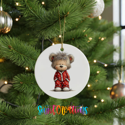teddy bear wearing red Christmas pajamas ceramic Christmas ornament hanging on a lit Christmas tree
