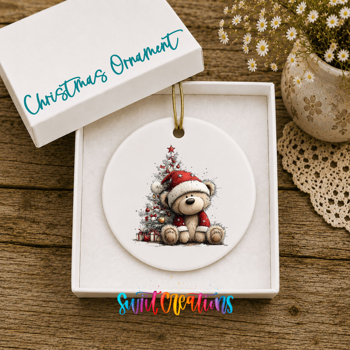 teddy bear sitting beside a decorated Christmas tree ceramic Christmas ornament presented in a gift box