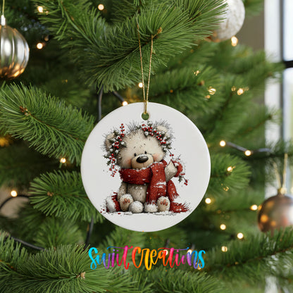 teddy bear with a red scarf and winter greenery ceramic Christmas ornament hanging on a lit Christmas tree