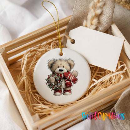 teddy bear with a red striped scarf and holly wreath ceramic Christmas ornament displayed in a wooden gift crate