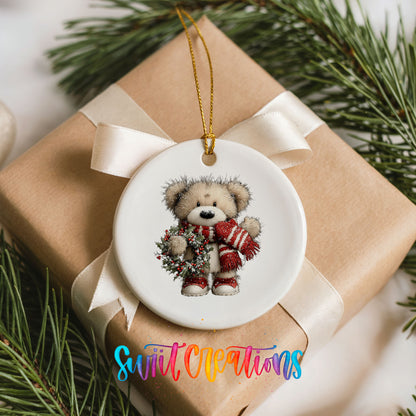 teddy bear with a red striped scarf and holly wreath ceramic Christmas ornament displayed on a wrapped Christmas gift