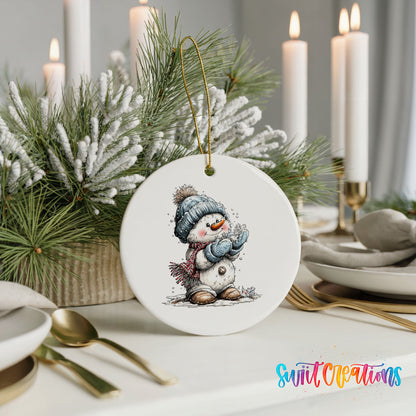 snowman in a blue hat holding a snowball ceramic Christmas ornament shown in a holiday table setting