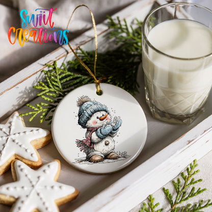 snowman in a blue hat holding a snowball ceramic Christmas ornament styled with holiday cookies and a candle