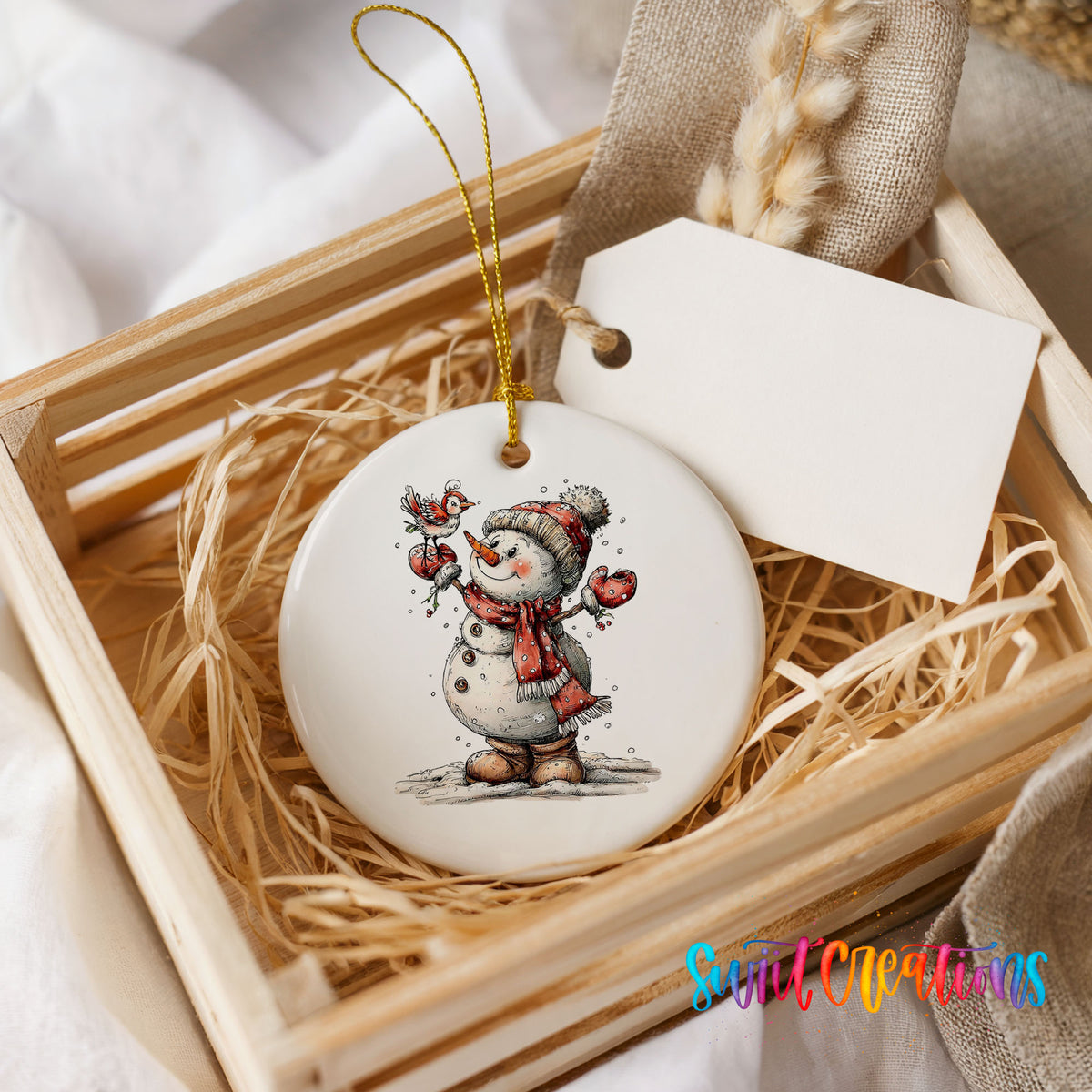 cheerful snowman waving in a red winter hat ceramic Christmas ornament displayed in a wooden gift crate
