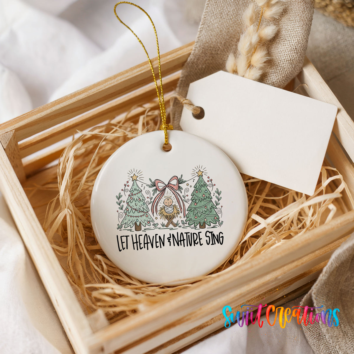 Let Heaven and Nature Sing church and winter trees design ceramic Christmas ornament displayed in a wooden gift crate
