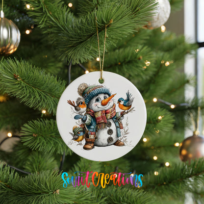 snowman in a blue hat with colorful winter birds ceramic Christmas ornament hanging on a lit Christmas tree