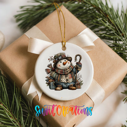 rustic snowman with a walking stick and plaid scarf ceramic Christmas ornament displayed on a wrapped Christmas gift