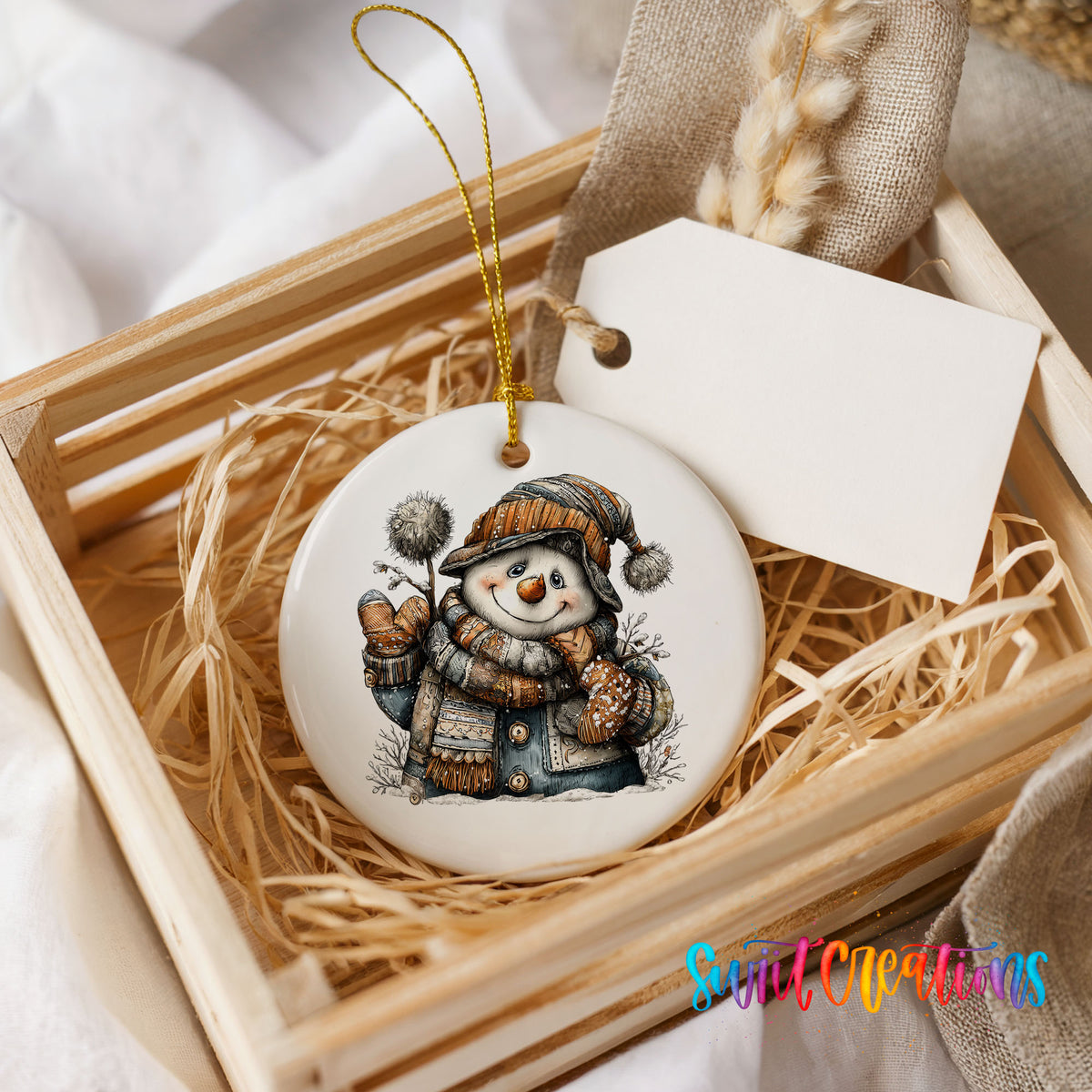 snowman in a striped knit hat and winter mittens ceramic Christmas ornament displayed in a wooden gift crate