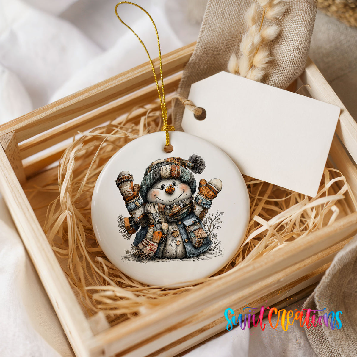 cheerful snowman raising striped winter mittens ceramic Christmas ornament displayed in a wooden gift crate